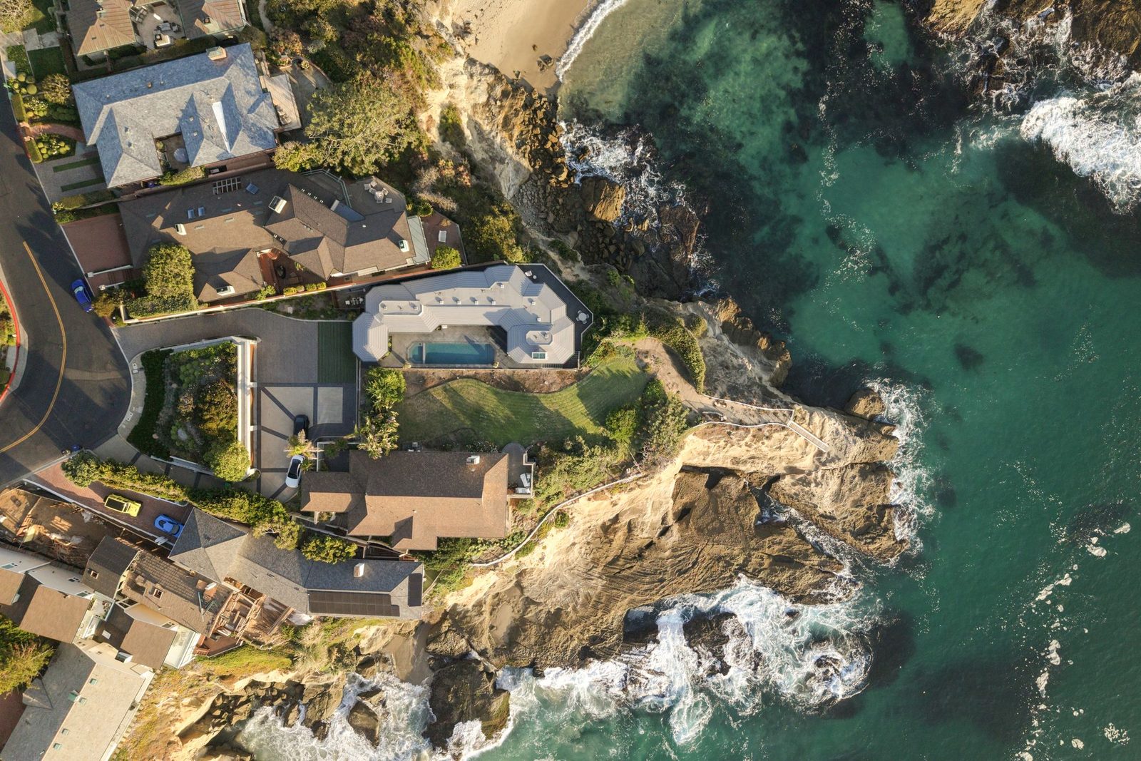 Aerial drone photograph of an oceanfront home above a cove